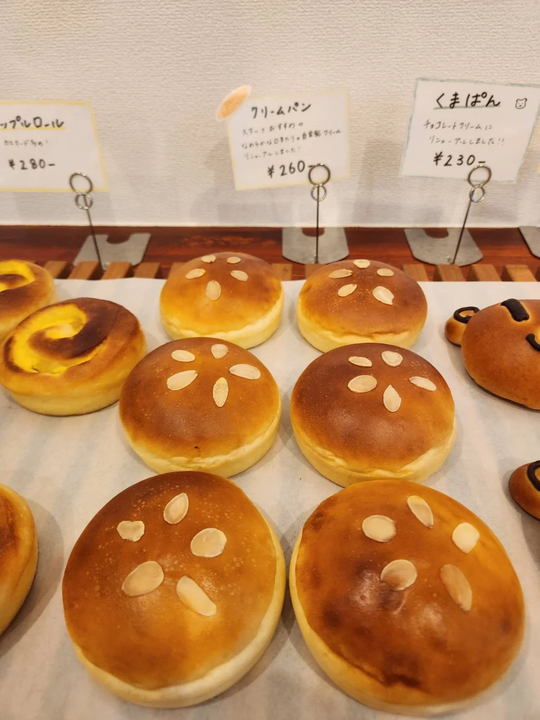 アーモンドをのせた丸いクリームパンが並ぶ、かごぱんの売り場